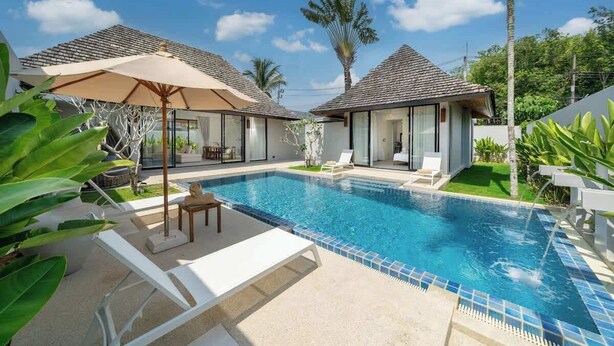 A swimming pool with lounge chairs and umbrellas, surrounded by palm trees and modern architecture.