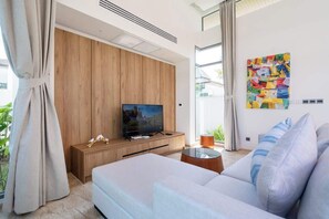 Ett modernt vardagsrum med en platt-TV, en väggpanel i trä och en färgstark, abstrakt målning.