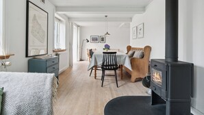 A room with a bed, a table with chairs, a fireplace, and a map on the wall. - Cozy fisherman's house near the sea (Rønne)