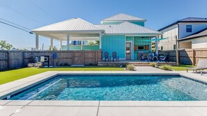 A residential backyard with a swimming pool, a covered patio, and a fenced area.