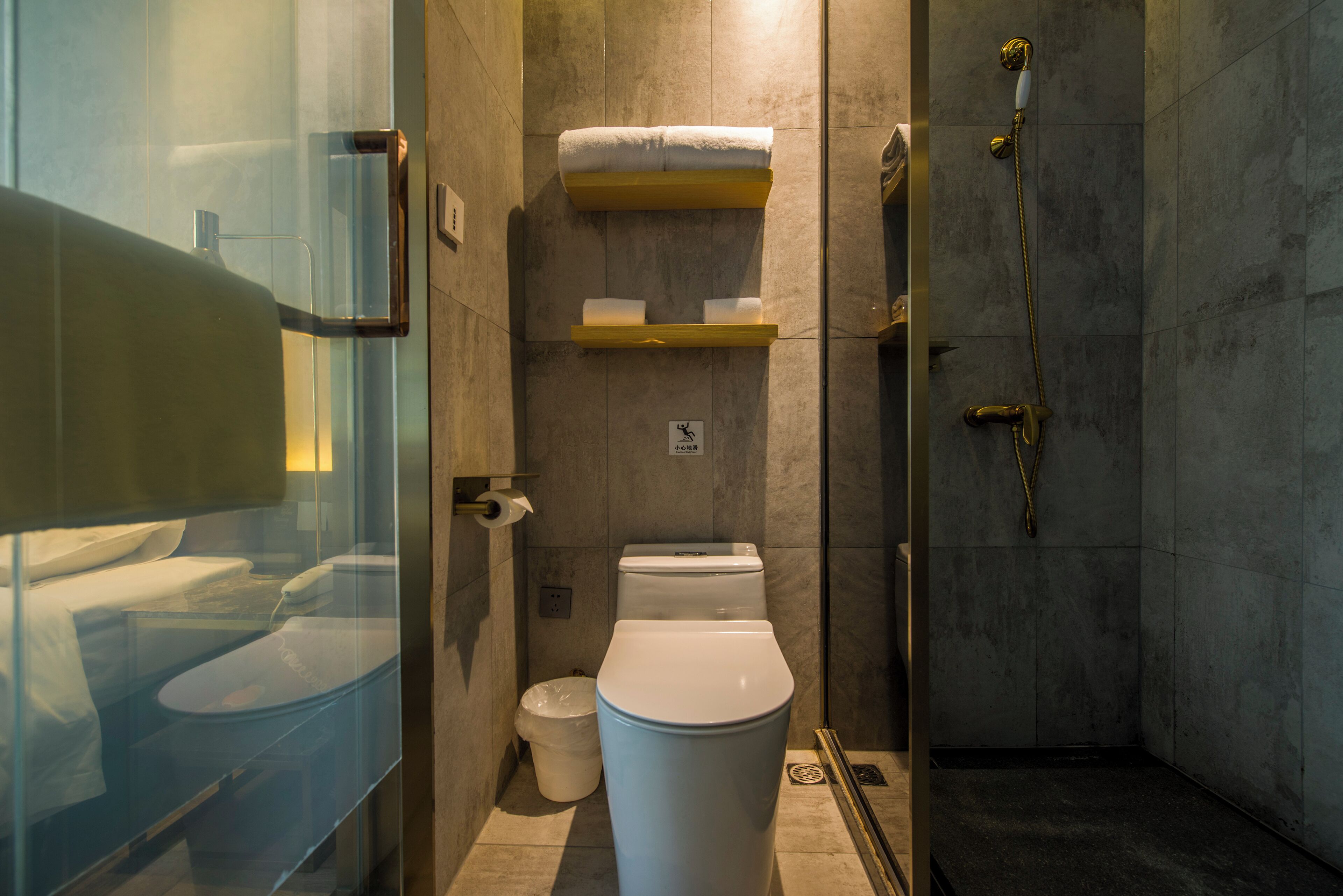 A modern bathroom with a glass shower enclosure, a toilet, and a bidet.