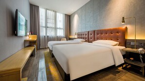 Une chambre d’hôtel avec deux lits, une télévision, un bureau et une lampe.