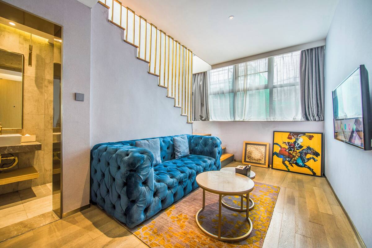 A modern living room with a blue sofa, a round coffee table, and a staircase leading to an upper level.