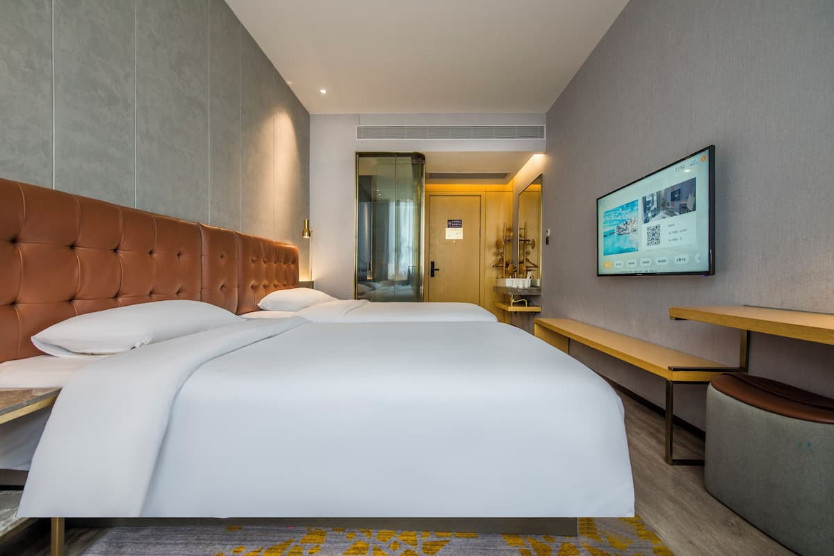A hotel room with a large bed, a desk, and a TV mounted on the wall.