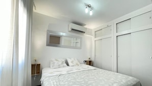 Ein Schlafzimmer mit einem Bett, einer Klimaanlage, einem Spiegel und einem Kleiderschrank.