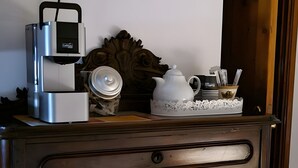 Une radio ancienne, une horloge décorée de motifs de tournesols et une machine à café posées sur un meuble en bois.