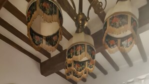 Une chambre à coucher comprenant un lit, une table de chevet, un ventilateur de plafond, une fenêtre avec des rideaux et un radiateur.