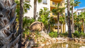 A courtyard with a water feature, palm trees, and a building with balconies.