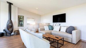 A modern living room with a sofa, coffee table, and a fireplace. - Maison Horizon – 3 Bedrooms/6 Guests – Sea View – 100m from Beach (Guilvinec)