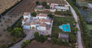 Vista aérea de una propiedad con varias edificaciones, una piscina y zonas ajardinadas circundantes.