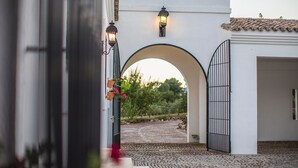 An arched entrance with a gated door, a pathway leading to a building, and a garden with potted plants. - Villa 'El Arroyo Ronda' with Mountain View, Wi-Fi and Air Conditioning (Ronda)