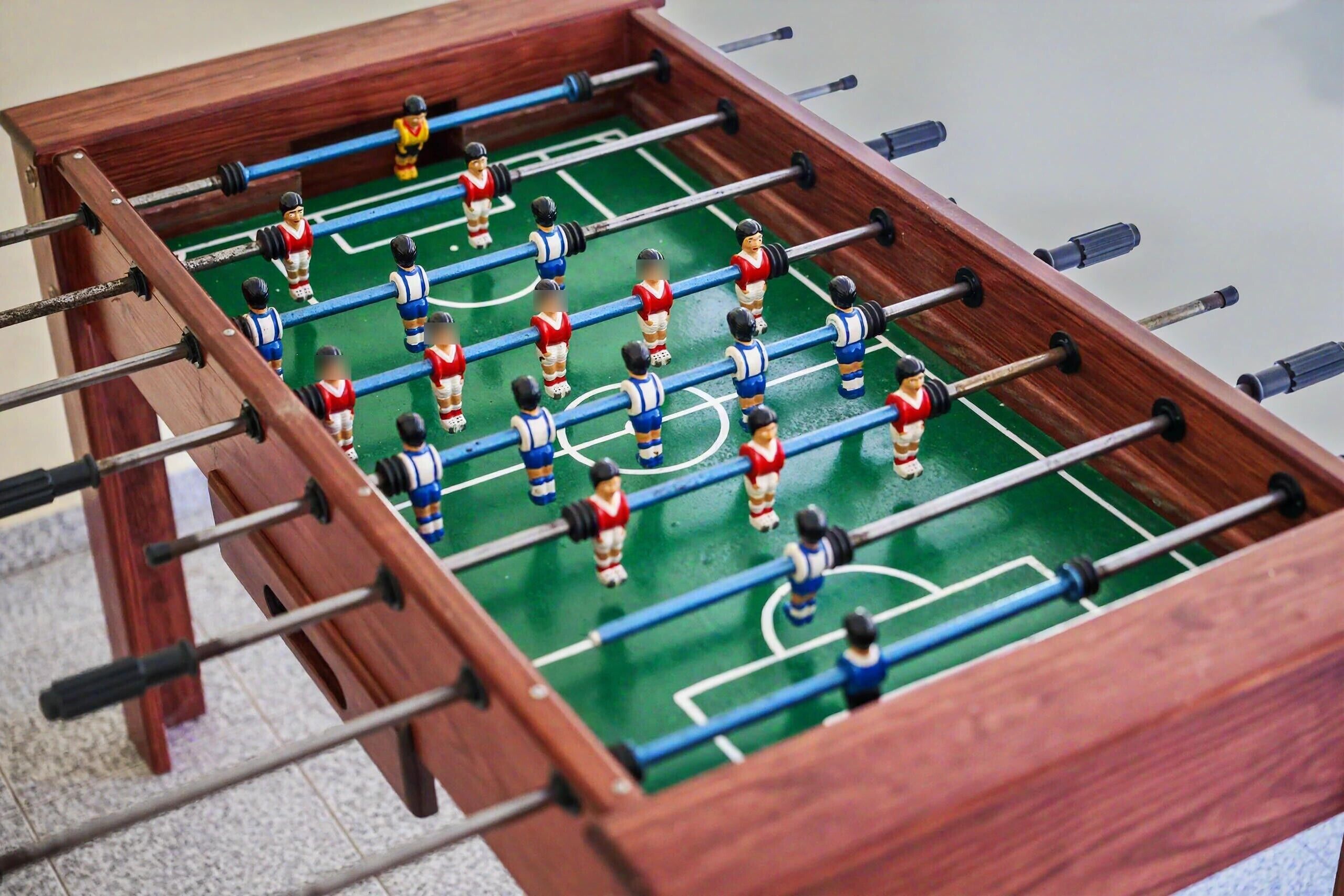 Ein Kicker mit Holzrahmen und grüner Spielfläche.
