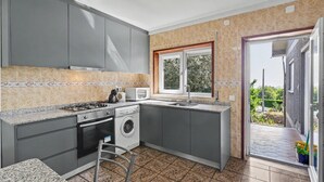 Una cocina compacta con armarios grises, microondas integrado, cocina a gas y lavadora.