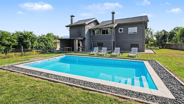 Una casa moderna de dos plantas con piscina, mobiliario exterior y un césped bien cuidado.