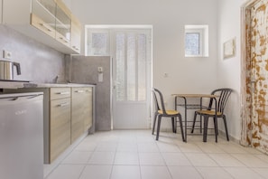 A kitchen with a dishwasher, wooden cabinets, a dining table with chairs, and a door with frosted glass panels. - Apartment 'Bel Momento - Family Room' with Sea View, Wi-Fi and Air Conditioning (Alikanas)