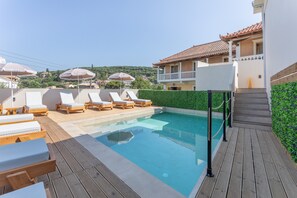 Un espace piscine avec des chaises longues et une terrasse en bois.