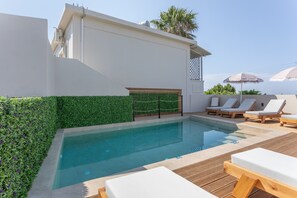 A swimming pool with lounge chairs, a wooden deck, and a green hedge. - Apartment 'Bel Momento - Family Room' with Sea View, Wi-Fi and Air Conditioning (Alikanas)