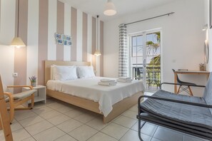 Une chambre à coucher comprenant un lit, des tables de chevet, une chaise, un bureau et un balcon avec vue.