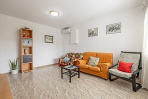 Un salon comprenant un canapé, un fauteuil, une table d’appoint, une bibliothèque et une plante en pot.