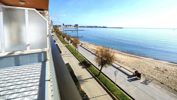 En balkon med udsigt over en strand og havet.