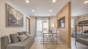 Una sala de estar moderna con sofá, mesa de comedor, sillas, litera y un cuadro grande en la pared.