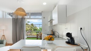 A modern kitchen with a white countertop, a bowl of fruit, a coffee maker, and a view of the outdoors. - Vacation 'Beautiful Sea View and Pool Finca 1' with Shared Pool, Private Terrace and Wi-Fi (Adeje)