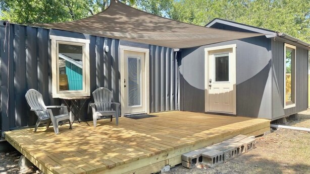 A small, single-story house with a covered porch, two doors, and a small table with chairs. - Club Casita . Unique Stay . Easy to Airport (Austin)