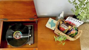 Un meuble en bois contenant une platine vinyle, un panier rempli de collations, une plante et une carte sur le thème du Texas.