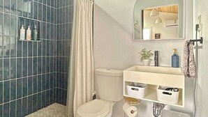 Une salle de bain équipée d’une douche, de toilettes, d’un lavabo et d’un miroir.