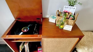Un meuble en bois sur lequel on trouve un disque vinyle, une petite plante et un panier rempli d’en-cas.