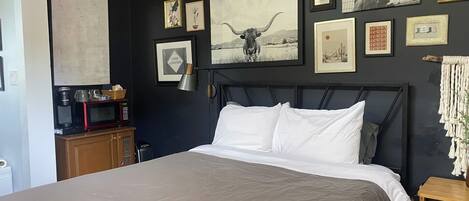 A bedroom with a large bed, a wooden headboard, and a wall decorated with various framed pictures and a map.
