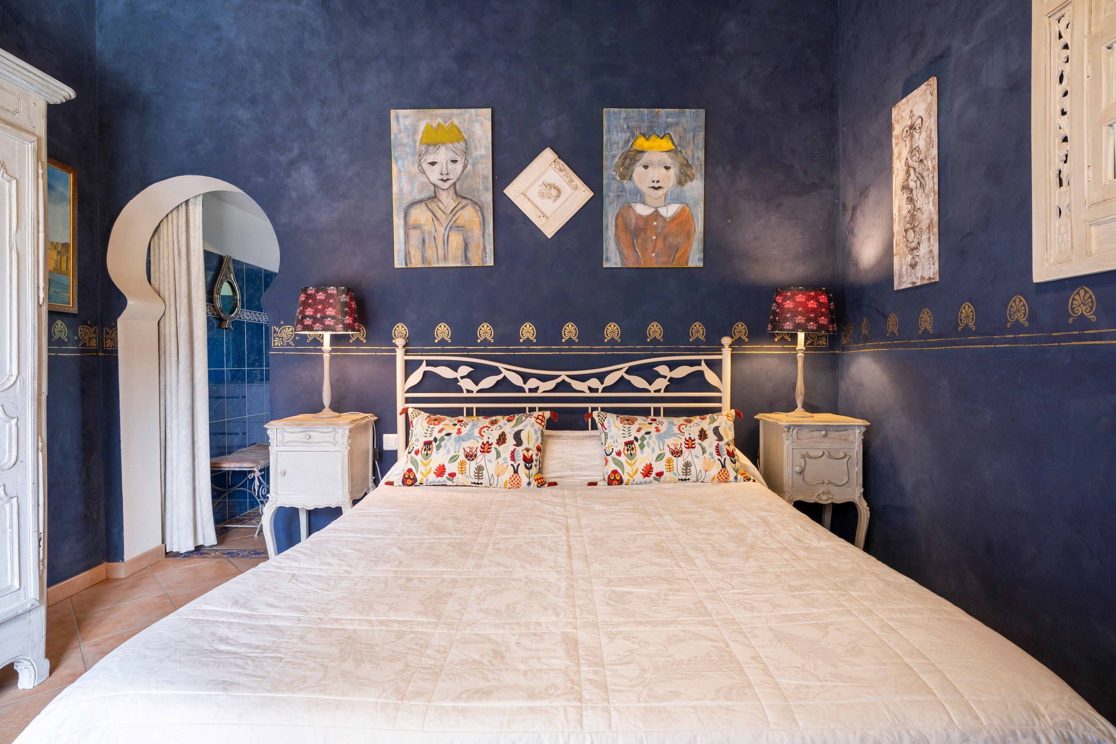 Een slaapkamer met een groot bed, twee nachtkastjes en een spiegel.