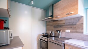 Cozinha moderna com eletrodomésticos de aço inoxidável, armários de madeira e painel de azulejos.