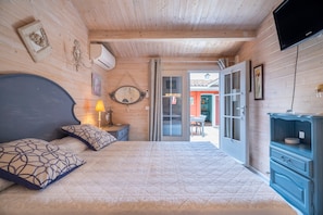 Una stanza con rivestimento in legno, un letto, una cassettiera, una televisione e una porta che dà sull'esterno.