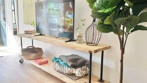 Un meuble en bois pour la télévision, avec un téléviseur à écran plat, un panier et une plante.