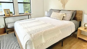 Une chambre à coucher avec un lit, une table de chevet et une fenêtre.