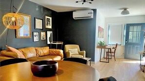 Un salon moderne avec une table ronde en bois, un canapé en cuir et un coin repas comprenant une petite table et des chaises.