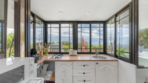 A modern kitchen with a built-in stove, microwave, and sink, large windows with a view, and a wooden countertop. - Vacation 'Beautiful Sea View and Pool Finca 3' with Shared Pool, Private Terrace and Wi-Fi (Adeje)