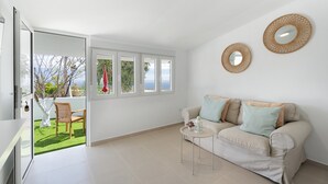 Een moderne woonkamer met een bank, een bijzettafeltje en twee spiegels aan de muur.