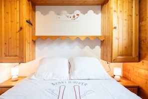 A wooden cabin-style bedroom with a bed, two bedside lamps, and a wall-mounted decoration. - Apartment "La Saulire" with Mountain Views, Private Terrace and Wi-Fi (Les Allues)