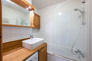 A bathroom with a wooden vanity, a white sink, a glass shower enclosure, and a white tiled wall. - Apartment "La Saulire" with Mountain Views, Private Terrace and Wi-Fi (Les Allues)