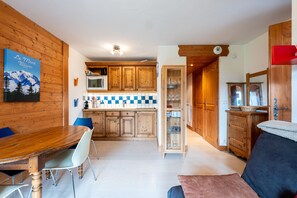 Un intérieur en bois comprenant une table à manger, des chaises, une cuisine avec des meubles en bois et une vitrine en verre.