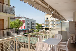 Ein Balkon mit Tisch und Stühlen, Blick auf die Straße und ein Gebäude mit Balkonen.