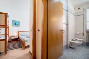 Ein Schlafzimmer mit Etagenbett, Nachttisch mit Lampe, kleinem Teppich und einem Wandbild.