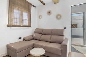 Una sala de estar moderna con un sofá modular, una mesita redonda y apliques decorativos de pared.