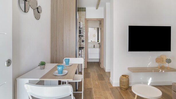 Una cocina moderna con comedor, televisor montado en la pared y techo de madera.