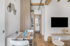 Una cocina moderna con comedor, televisor montado en la pared y techo de madera.