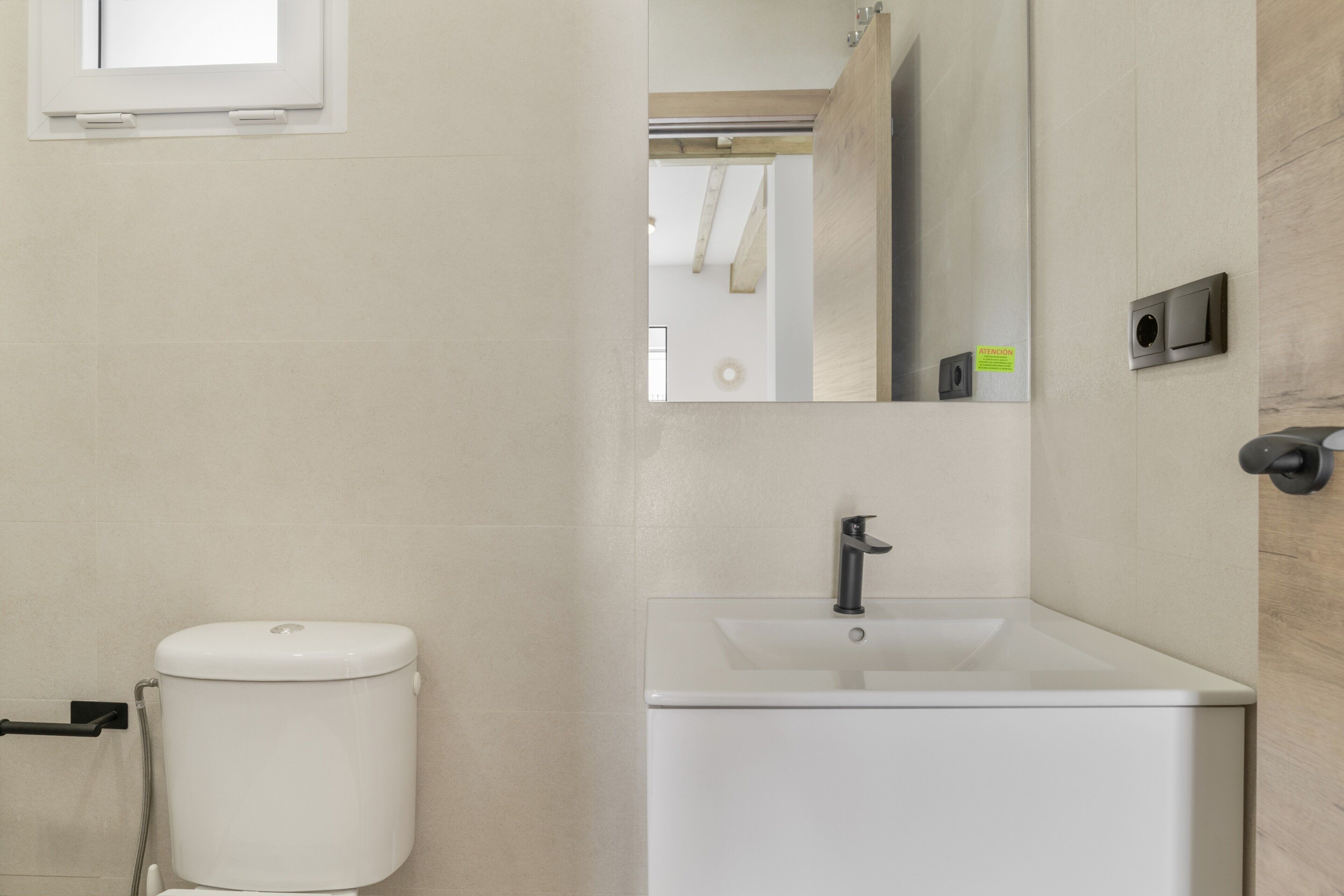 Ein Badezimmer mit Toilette, Waschbecken, Spiegel und Fenster.