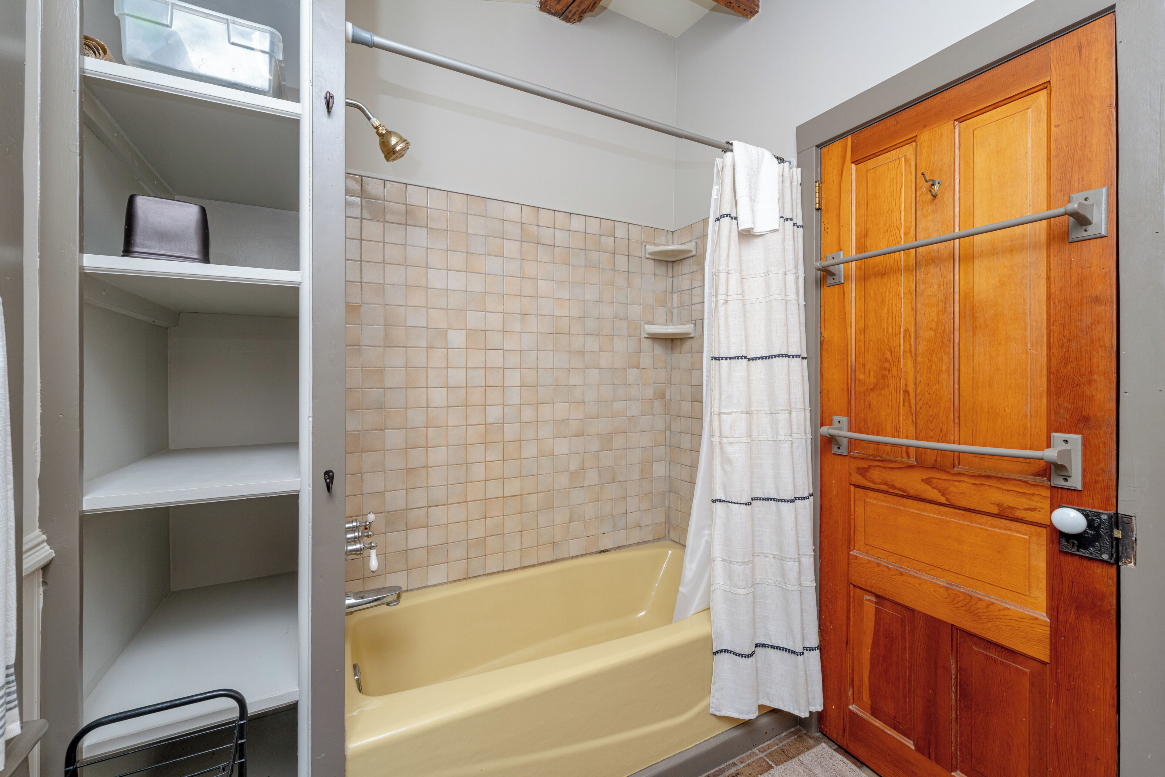 Ein Badezimmer mit einer Badewanne, einer Holztür und einem gefliesten Duschbereich.