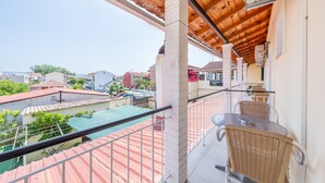 A balcony with a view of a swimming pool, a table with chairs, and a telephone.